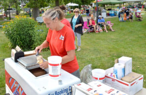 Dawn Yoder of Joe’s Ice Cream serves an ice cream cone while barely visible behind her is fellow employee Kristee Erquhart.
